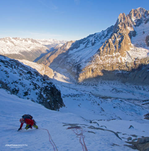 Ally on the first icefield as the sun rises over the Aiguille Verte and Drus